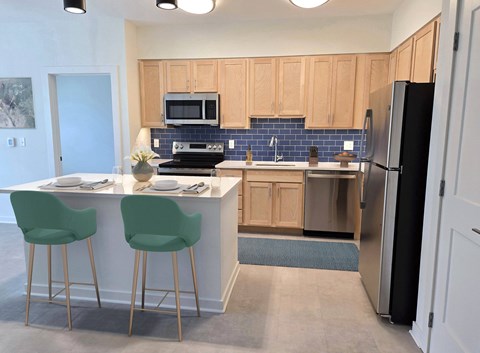 A kitchen with a white counter and green chairs.