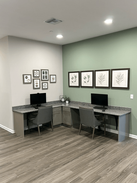 an office with two desks and two computers and pictures on the wall