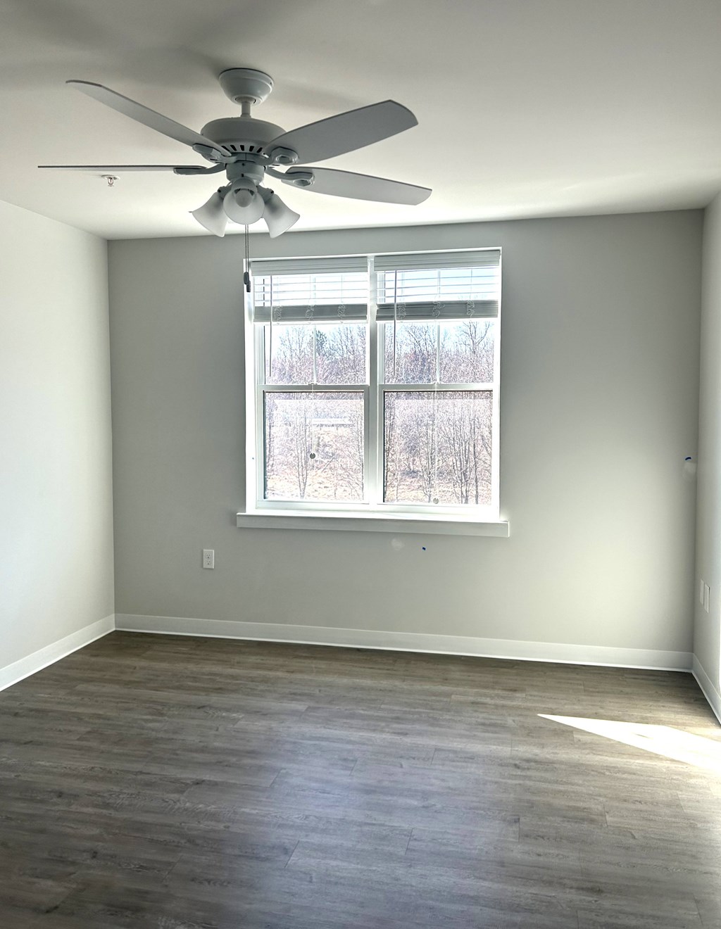 A room with a ceiling fan and a window.