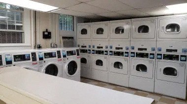 a laundry room filled with lots of white washers and dryers
