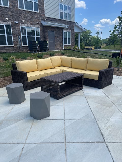 A yellow couch and black coffee table on a patio.
