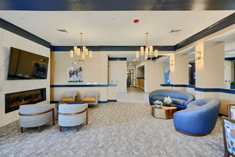 A spacious lobby with a fireplace, chairs, and a blue armchair.