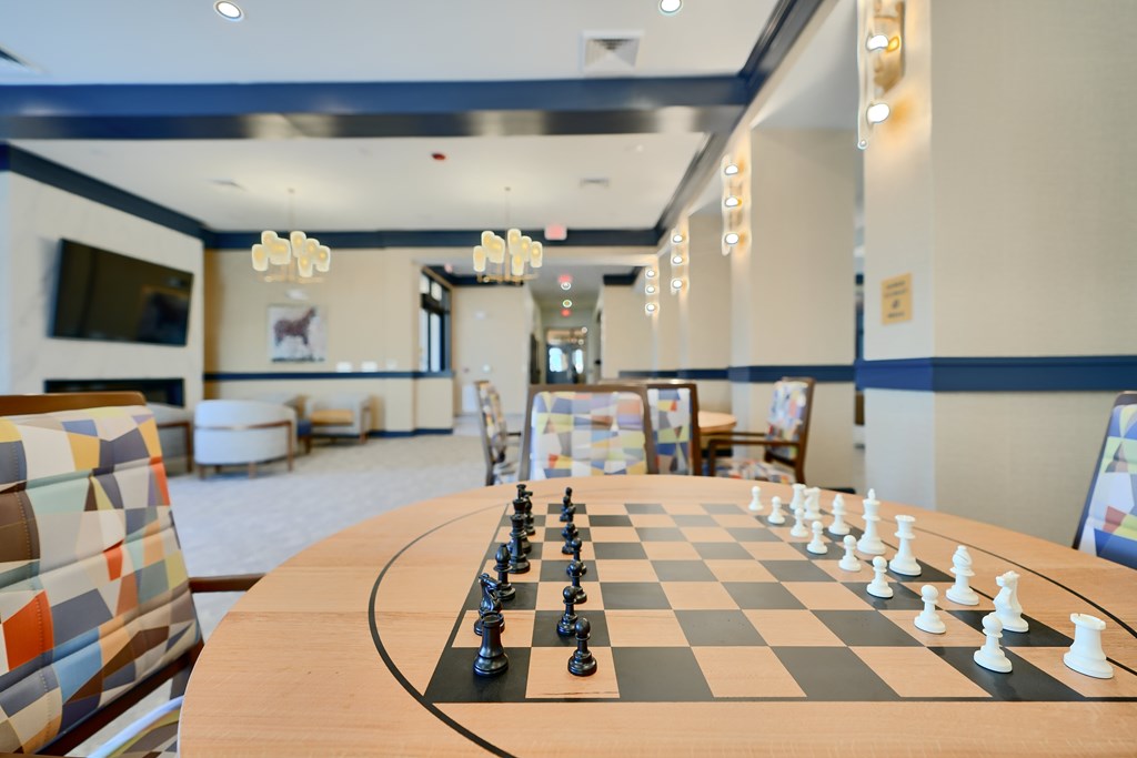 Now leasing senior 1-bedrooms in Baltimore, MD. A chess board with black and white pieces set up on a wooden table.