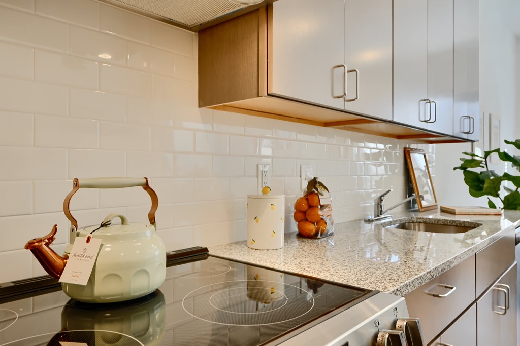 Now leasing senior 1-bedrooms in Baltimore, MD. A white kettle is on a black stove in a kitchen.
