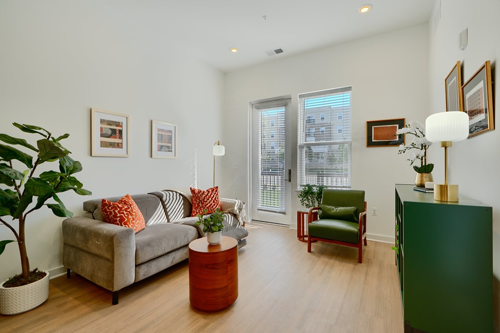 Now leasing senior 1-bedrooms in Baltimore, MD. A living room with a grey couch and a green chair.