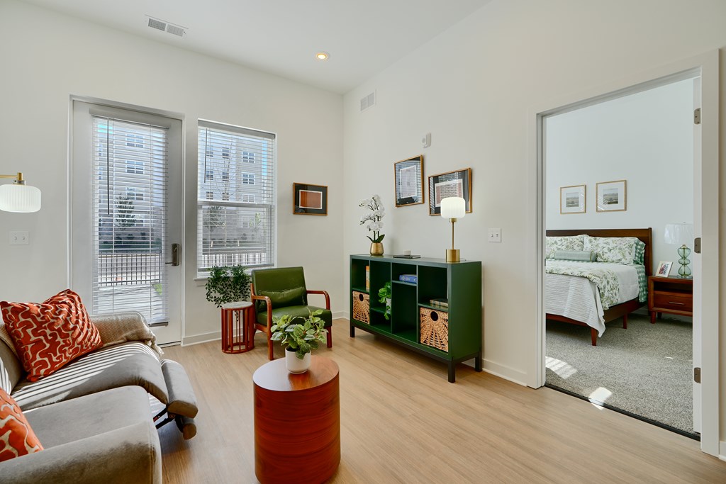 Now leasing senior 1-bedrooms in Baltimore, MD. A living room with a grey couch and a red pillow.