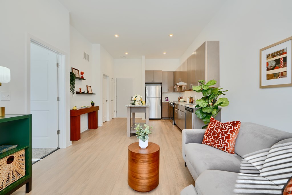 Now leasing senior 1-bedrooms in Baltimore, MD. A living room with a grey couch and a wooden coffee table.