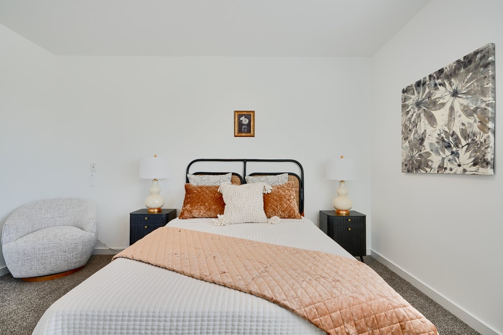 Now leasing senior 1-bedrooms in Baltimore, MD. A bedroom with a large bed and a chair.