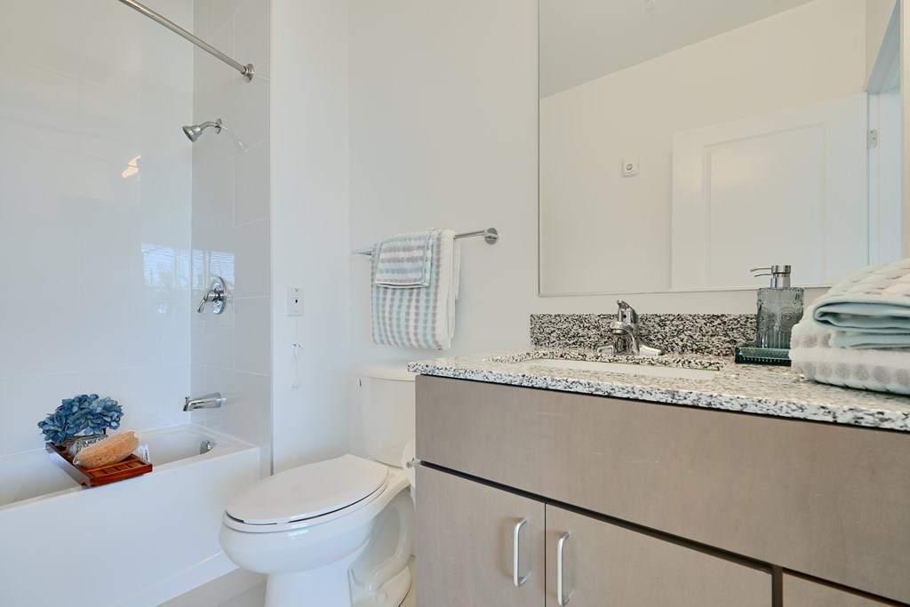 Now leasing senior 1-bedrooms in Baltimore, MD. A white toilet sits in a bathroom with a white tub and a white sink.