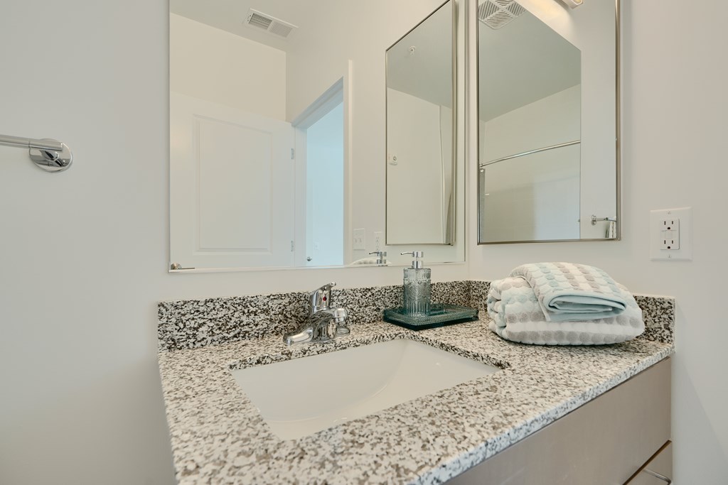 Now leasing senior 1-bedrooms in Baltimore, MD. A bathroom with a marble countertop and a large mirror.