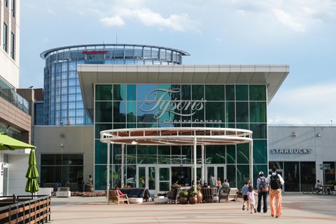 A large glass building with a curved roof and a sign that reads "Flyers" in front of a Starbucks.