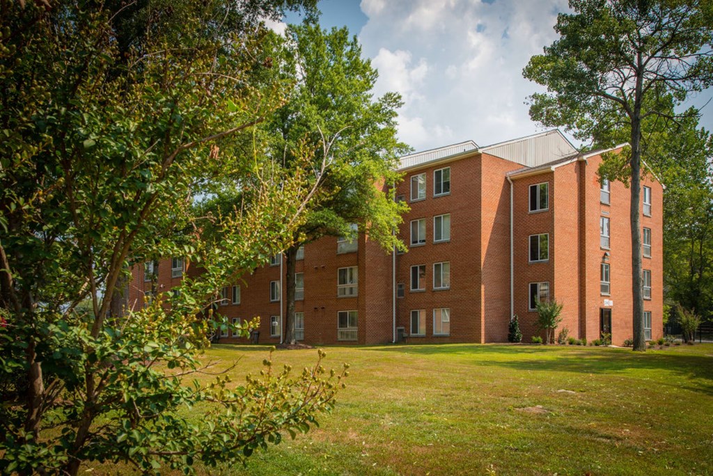 a large brick building with a green lawn and trees