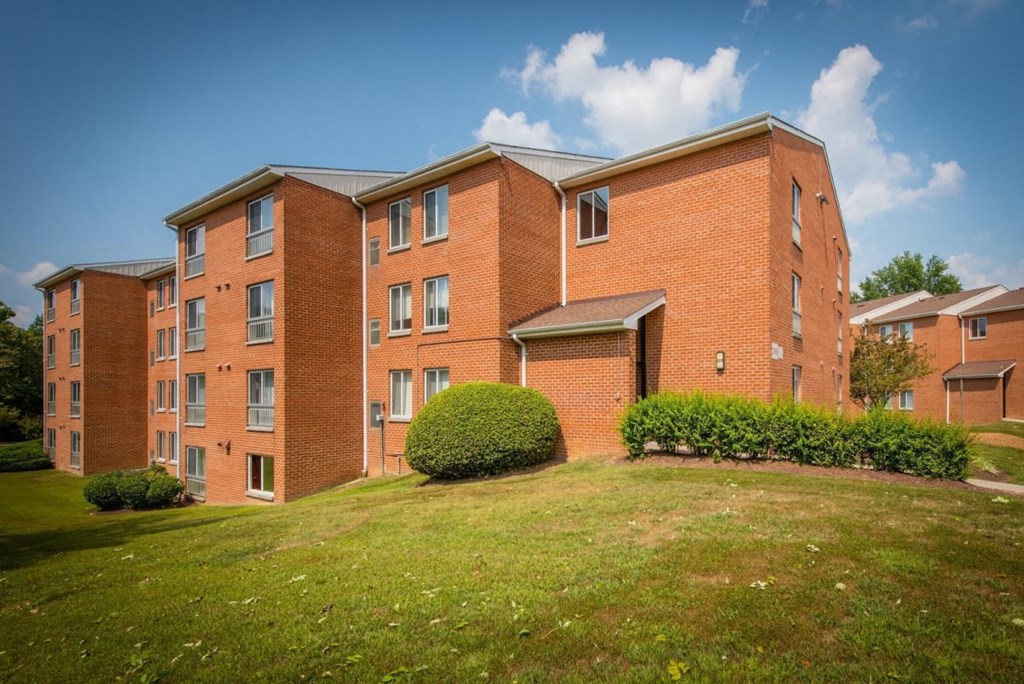 a large brick building with a green lawn in front of it