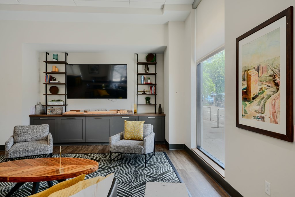 A living room with a grey couch, a wooden table, and a painting on the wall.