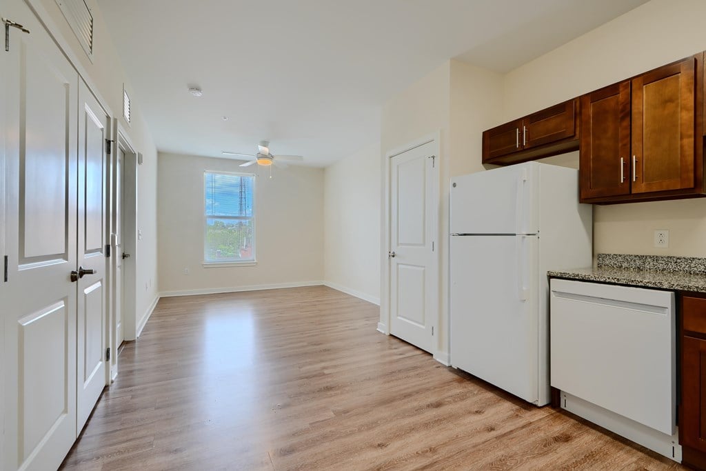 A kitchen with white appliances and wooden floors.