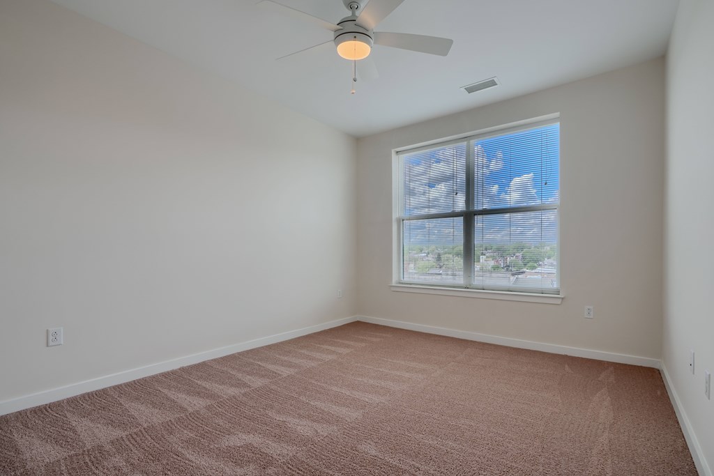 A room with a carpeted floor and a ceiling fan.