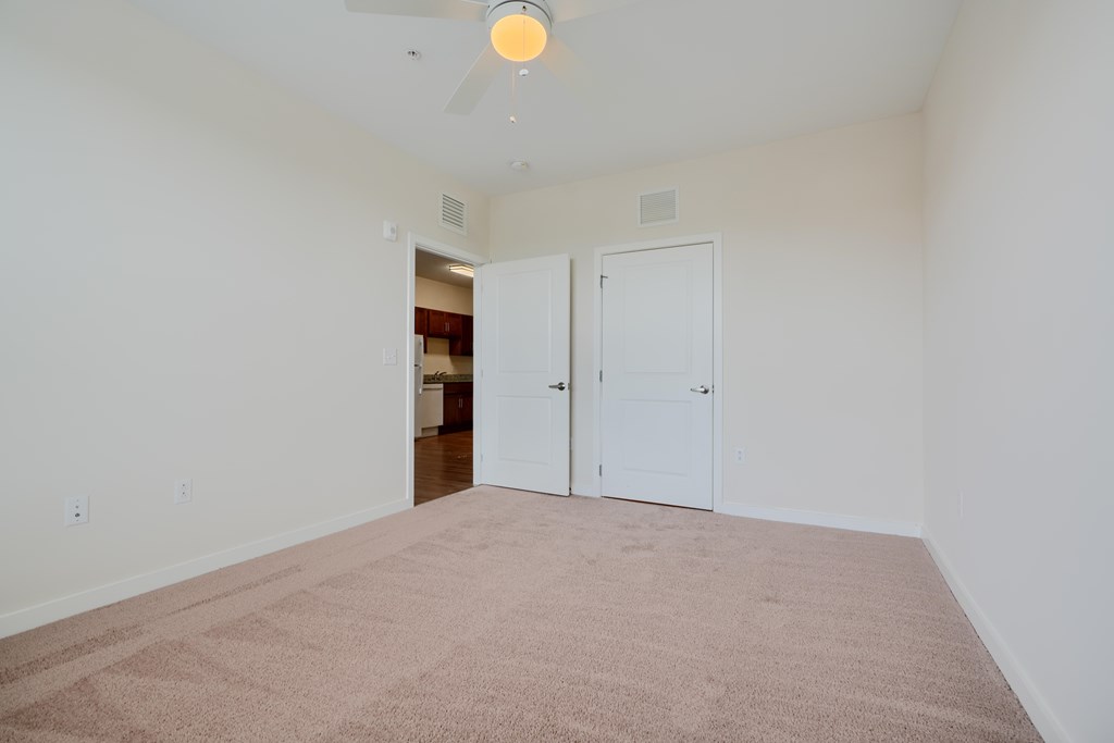 A room with a carpeted floor and a ceiling fan.