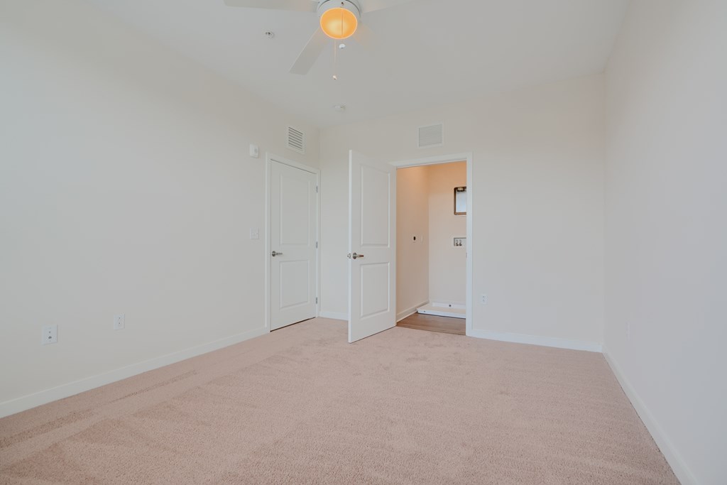 A room with a carpeted floor and a ceiling fan.