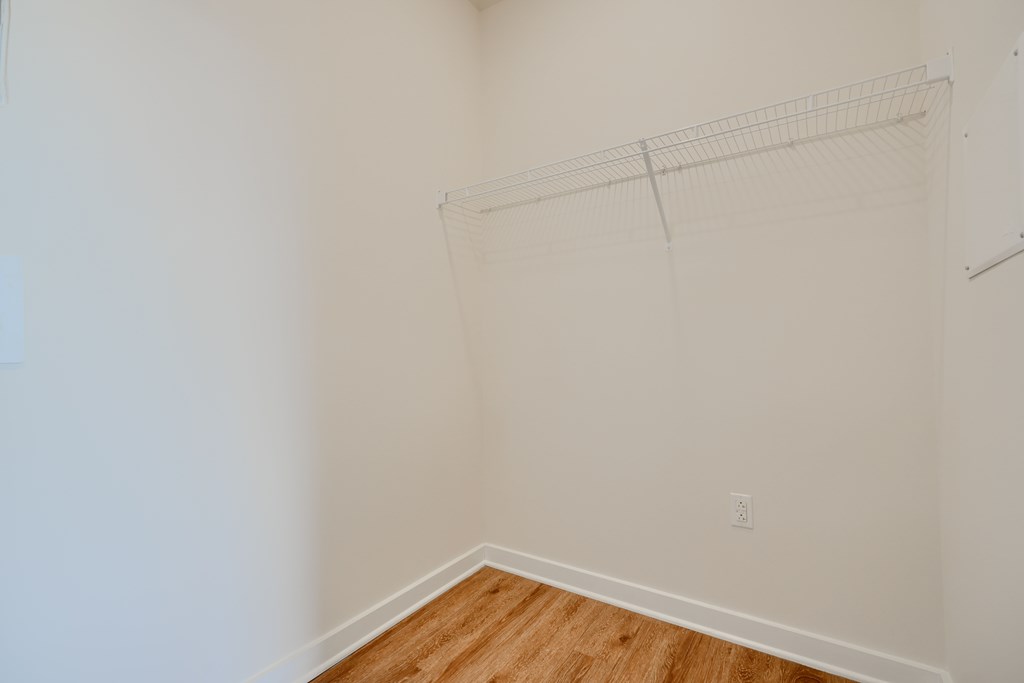 Empty room with a white wall and a wooden floor.