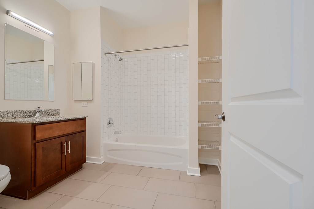 A white bathroom with a wooden vanity and a walk-in shower.