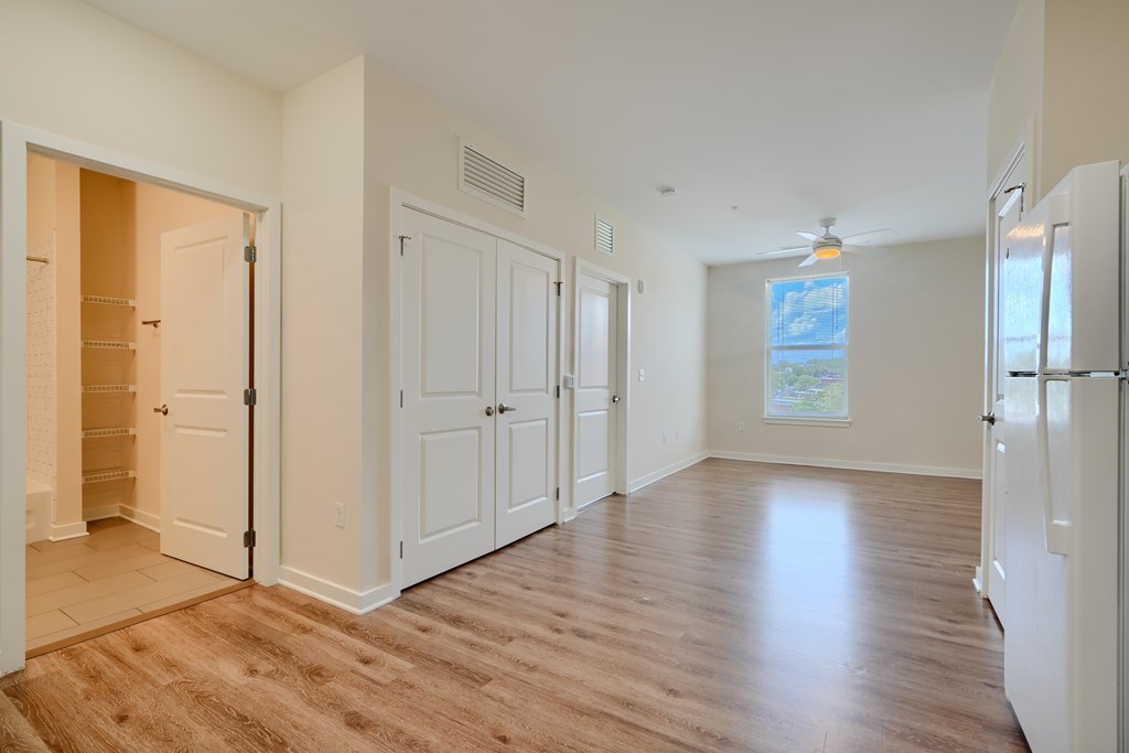 A kitchen area with a refrigerator, cabinets, and a window.