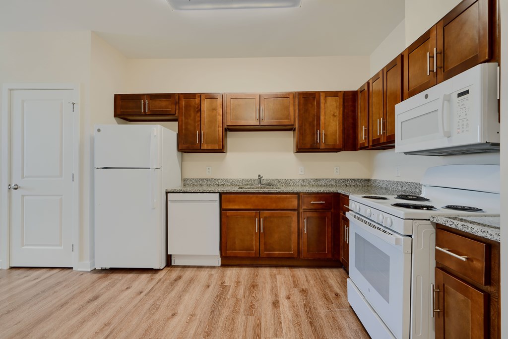 A kitchen with white appliances and wooden cabinets.