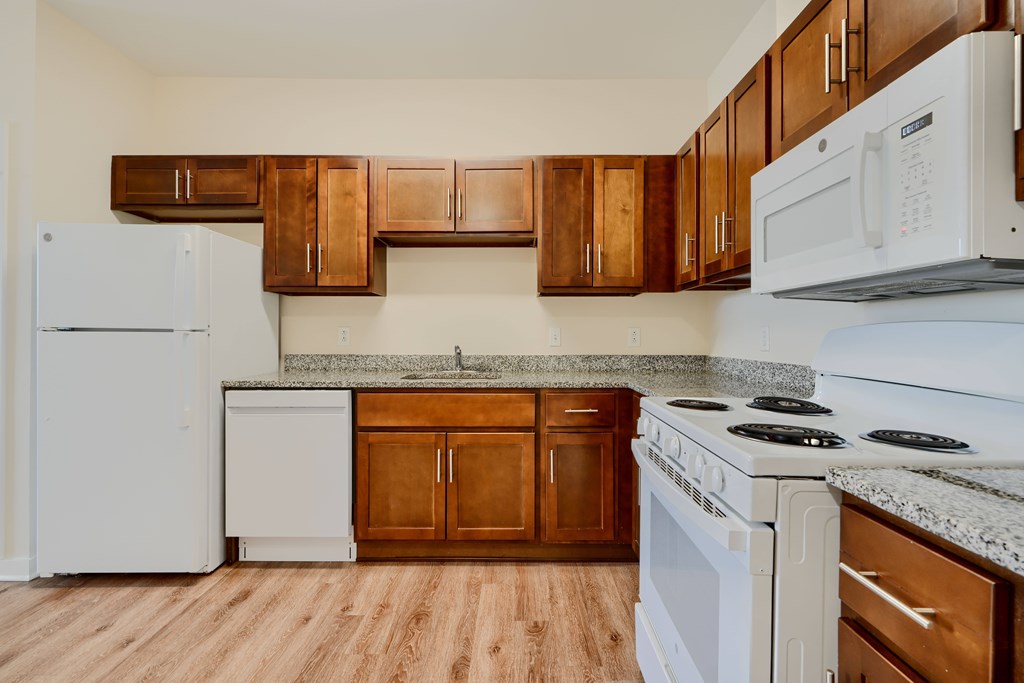 A kitchen with white appliances and wooden cabinets.