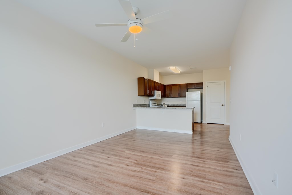 A room with a ceiling fan and wooden flooring.