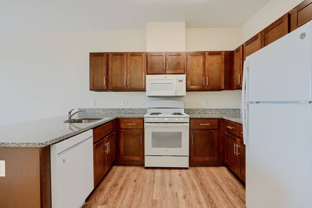 A kitchen with white appliances and brown cabinets.