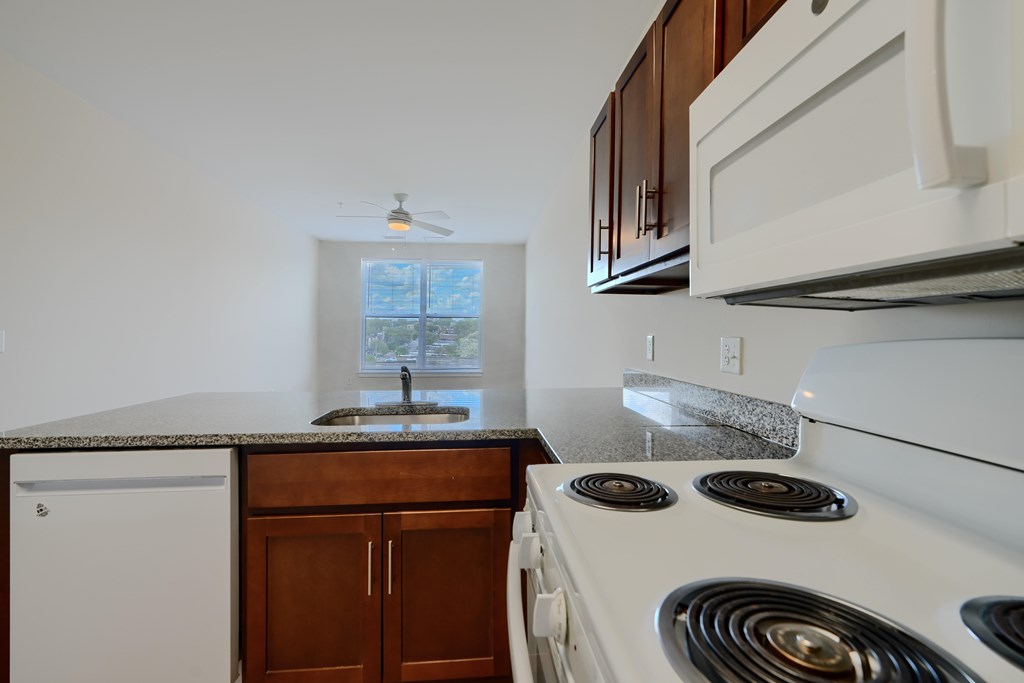A kitchen with a white stove top oven and a white dishwasher.