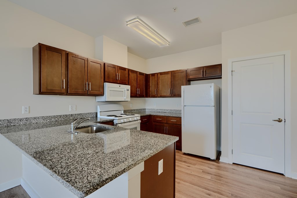 A kitchen with granite countertops and white appliances.