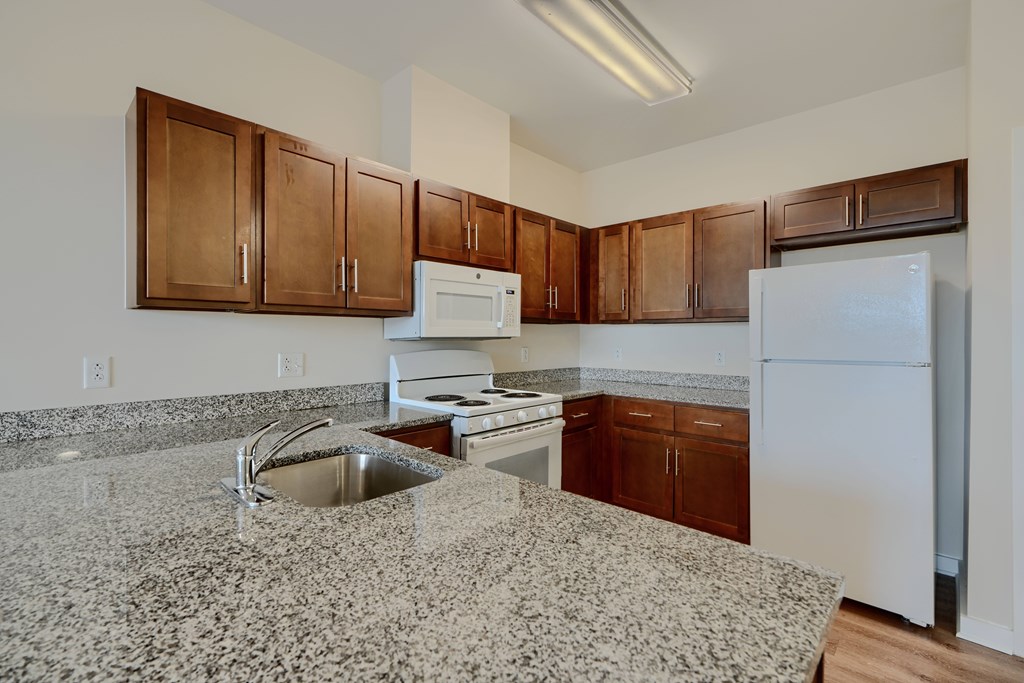 A kitchen with granite countertops and white appliances.