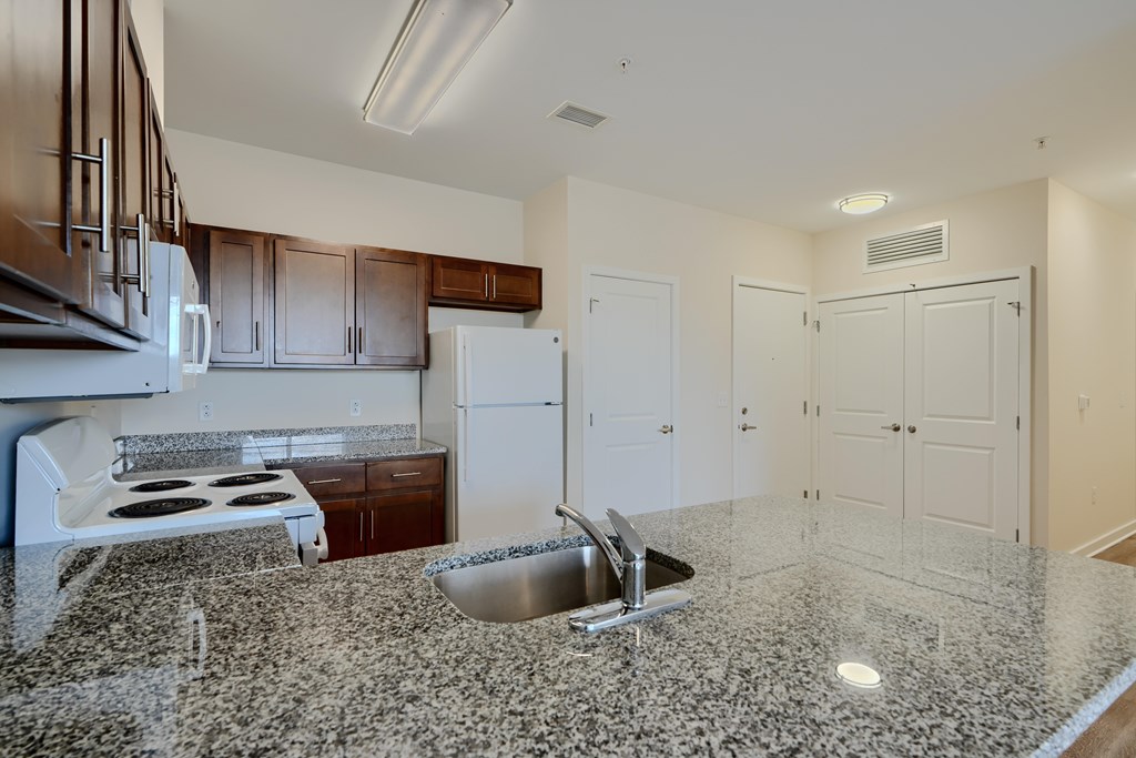 A kitchen with granite countertops and white appliances.