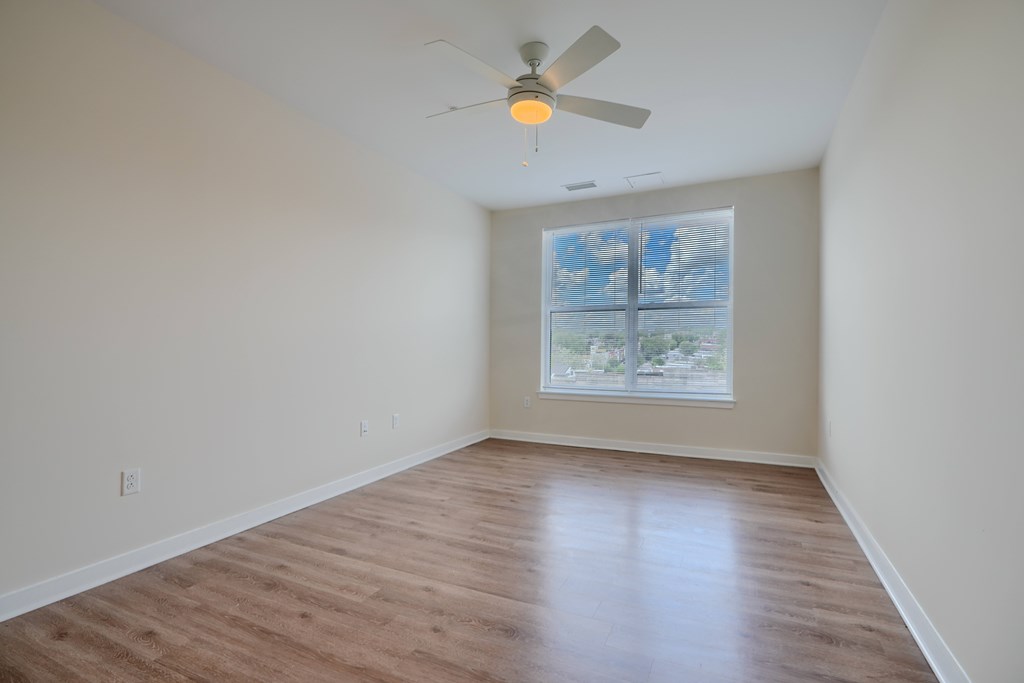 A room with a ceiling fan and a window overlooking a cityscape.