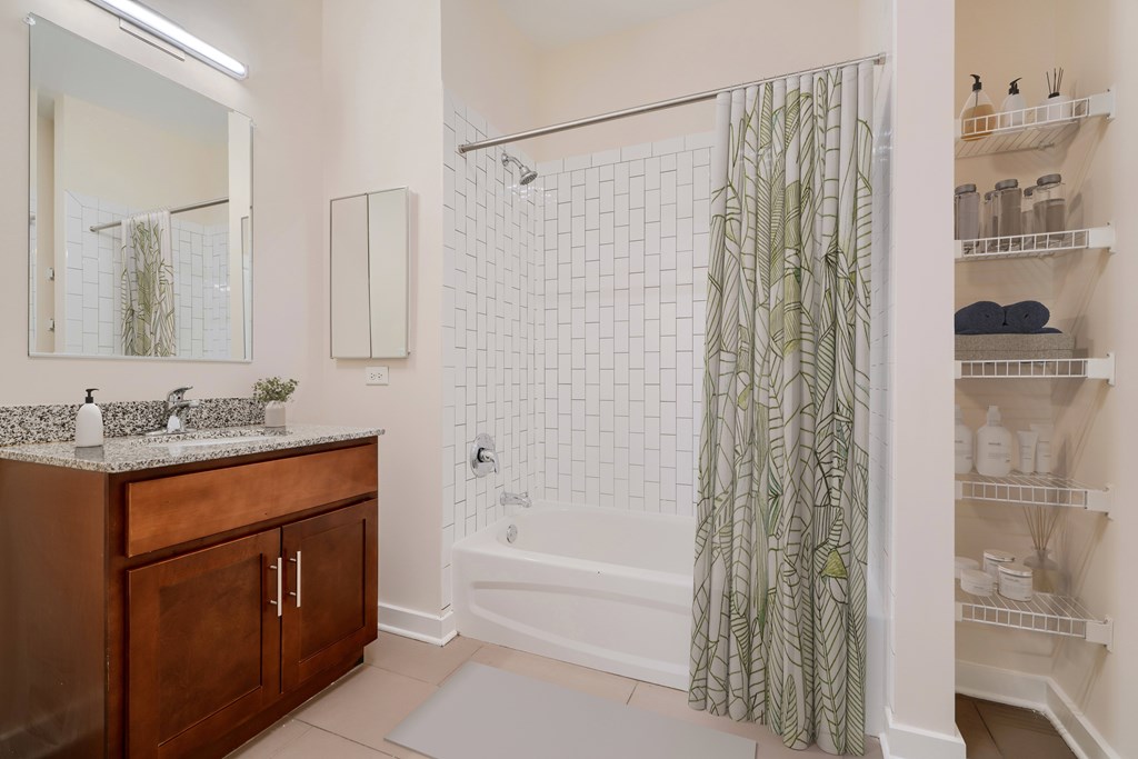 A bathroom with a white tiled shower and green shower curtain.