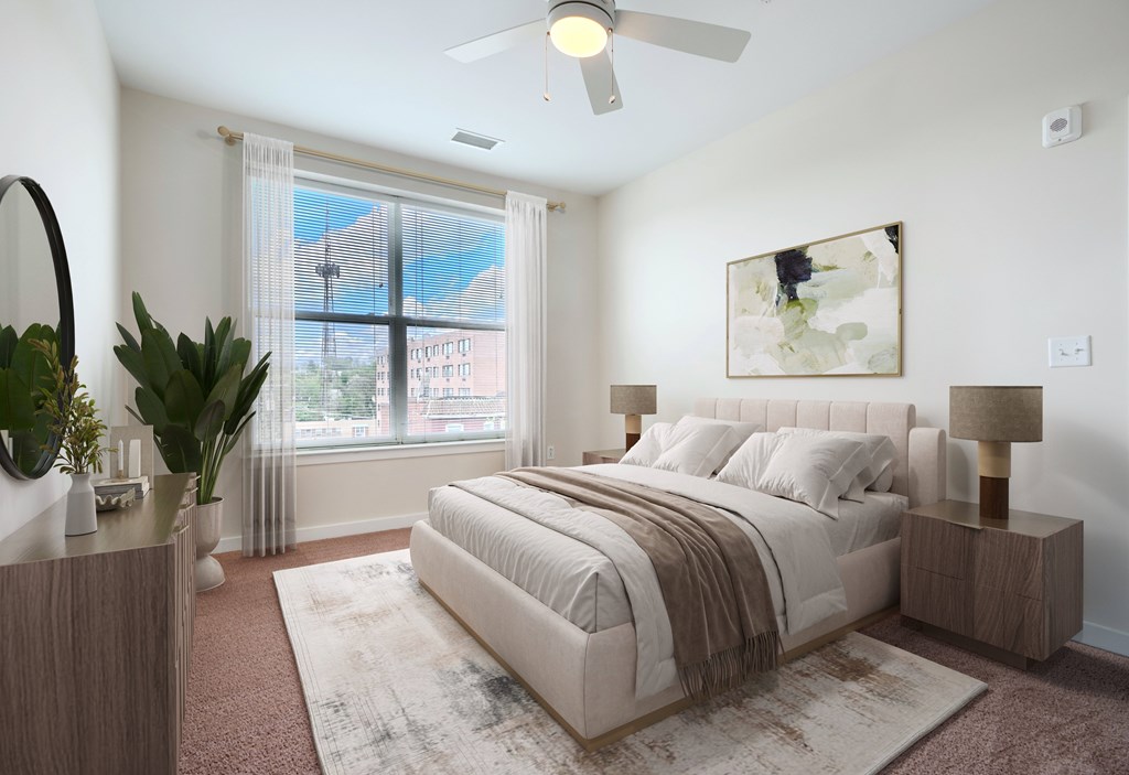 A bedroom with a large bed, a ceiling fan, and a window with a view of the outdoors.