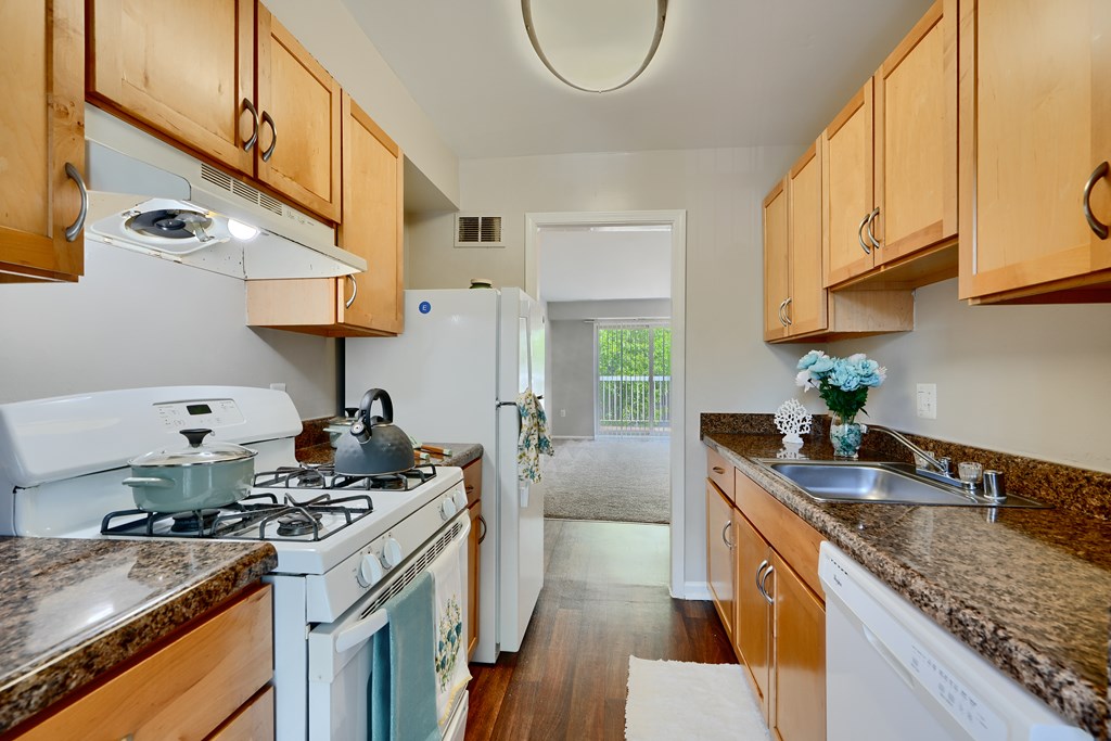 A kitchen with a white stove top oven and wooden cabinets.