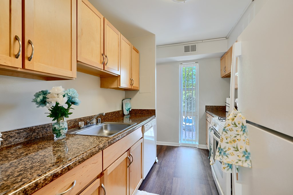 A kitchen with wooden cabinets and a granite countertop.