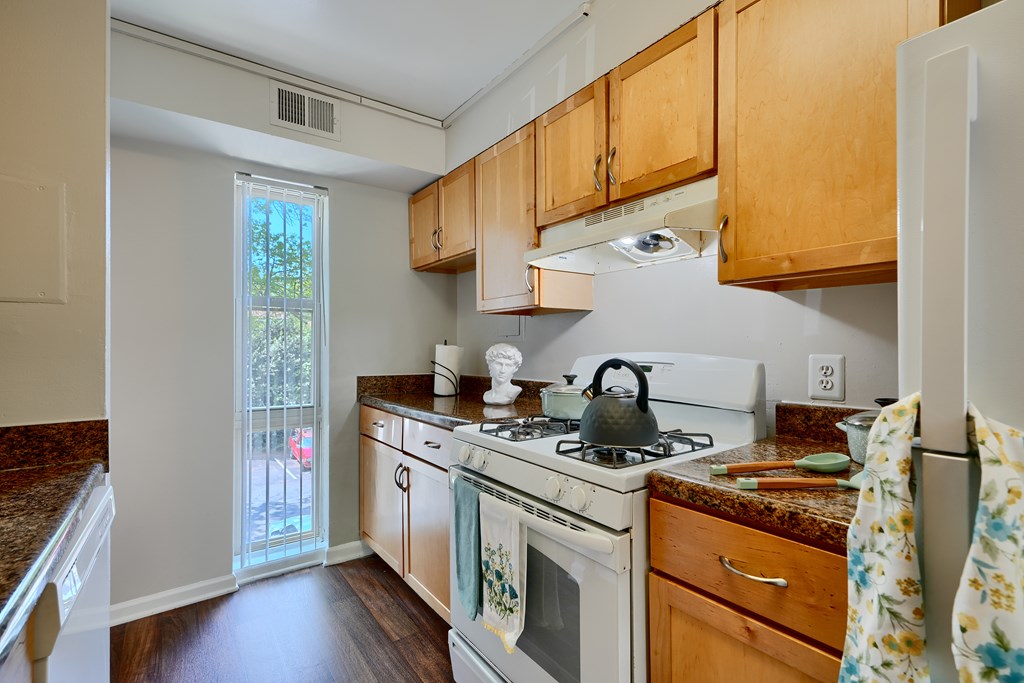 A kitchen with a white stove top oven and wooden cabinets.