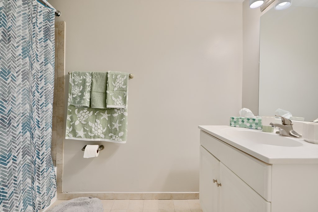 A bathroom with a white sink and a green and white towel hanging on the wall.
