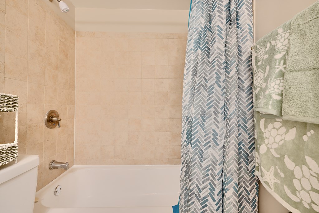 A bathroom with a white tub and a shower curtain.