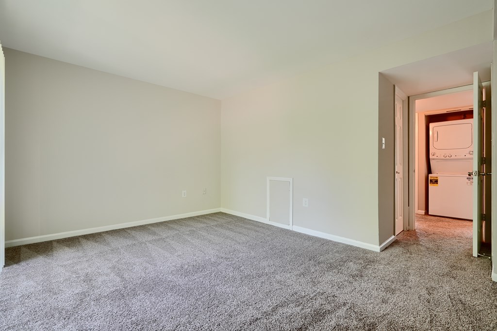A room with a carpeted floor and a door on the right side.