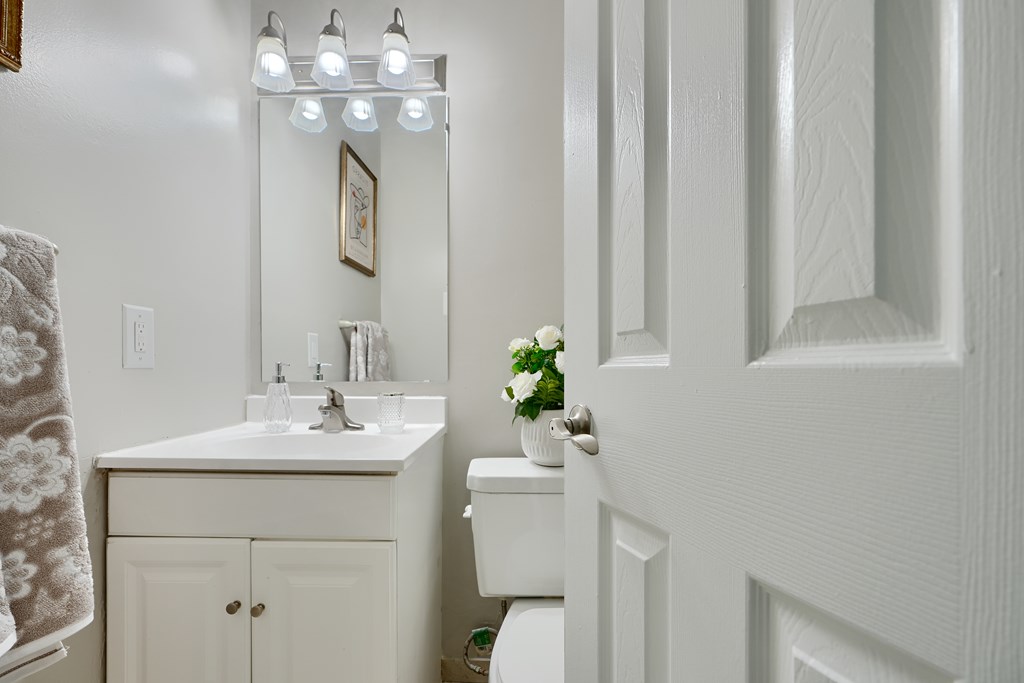 A white bathroom with a sink, mirror, and toilet.