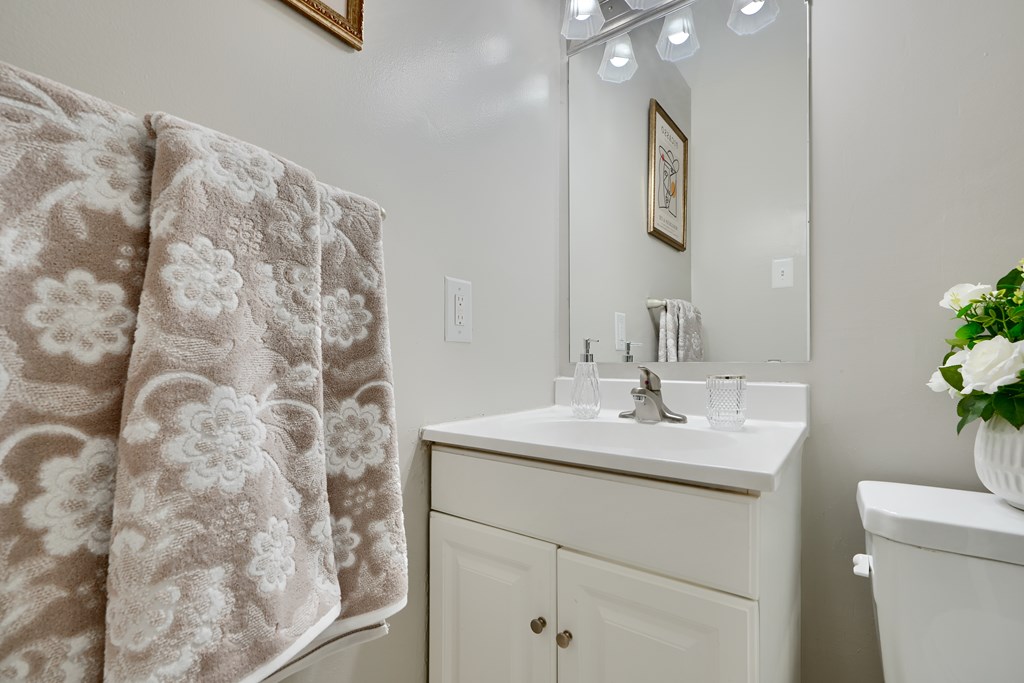 A bathroom with a floral towel hanging on the shower curtain.
