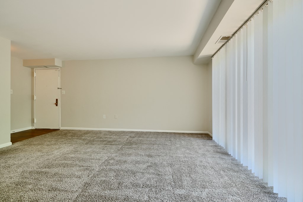 A room with a carpeted floor and a door on the left side.