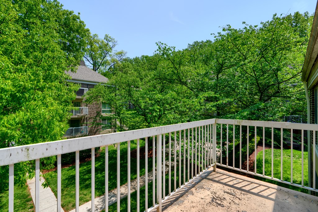 A white railing overlooks a lush green yard.
