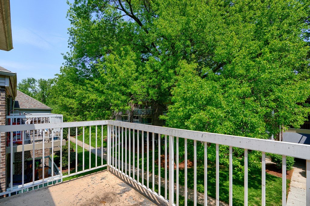 A white railing overlooks a yard with a tree.