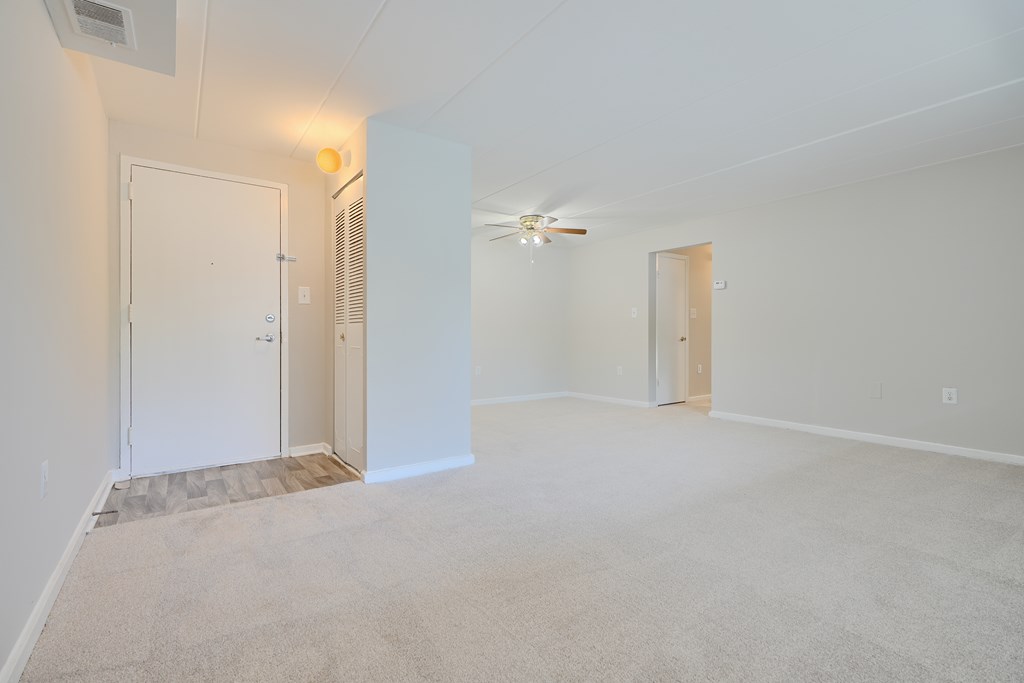 A spacious room with a ceiling fan and two doors.