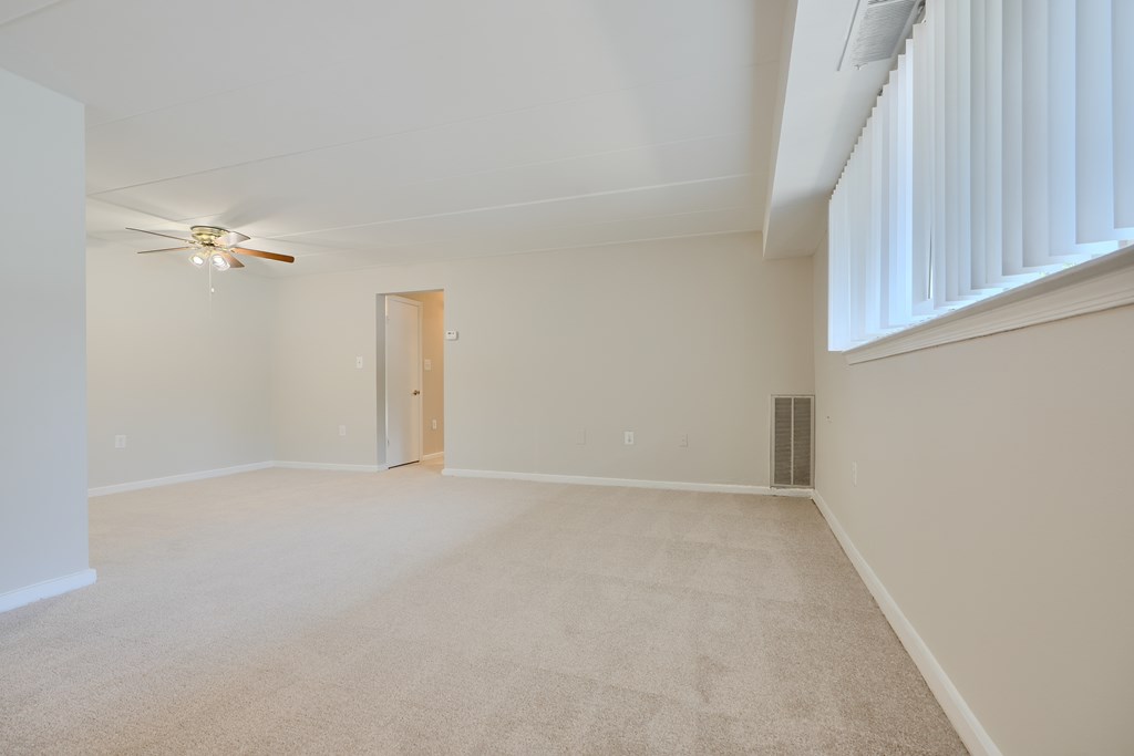 A room with a ceiling fan and carpeted floor.