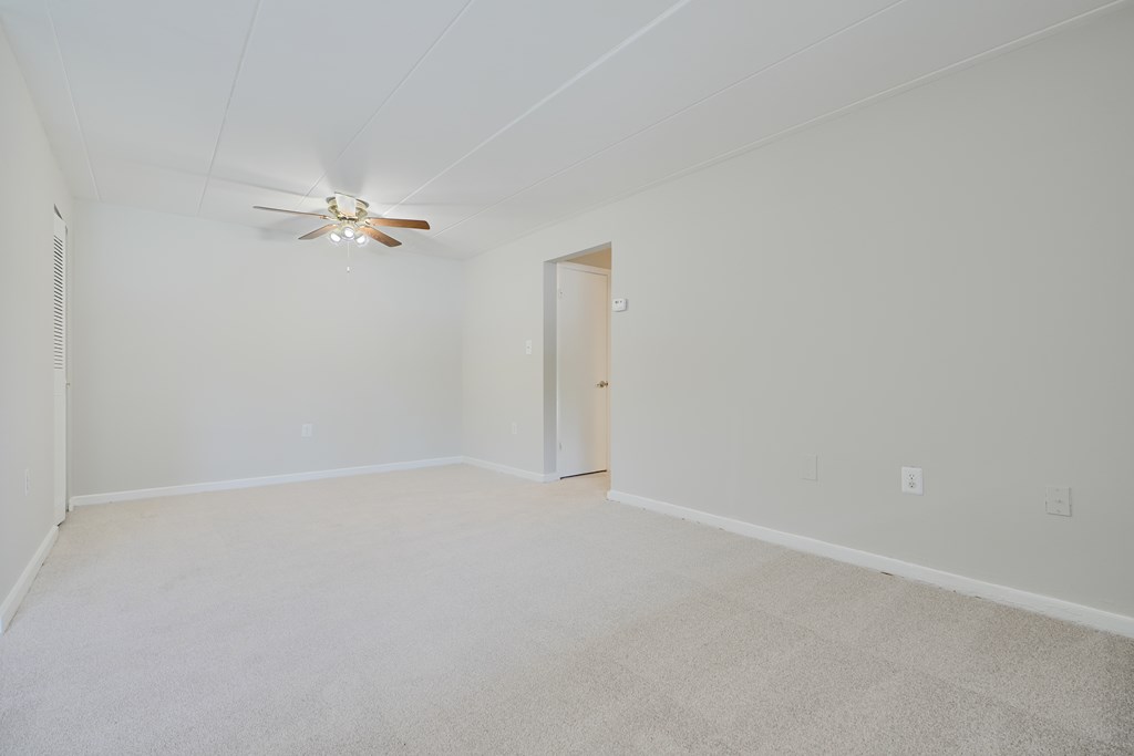 A room with a ceiling fan and carpeted floor.